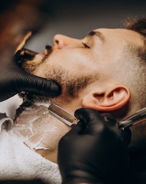 Handsome man cutting beard at a barber shop salon